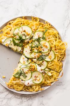 a pizza with zucchini, cheese and herbs cut into slices on a plate