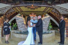 a bride and groom exchanging vows in front of a stone fountain at their wedding ceremony