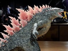 a toy godzilla with its mouth open and pink spikes on it's back legs