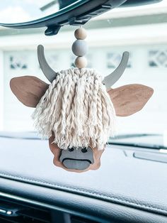 an animal head hanging from the dashboard of a car with long hair and horns on it