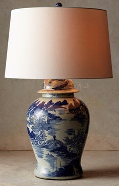 a blue and white vase with a light on it sitting next to a lamp shade