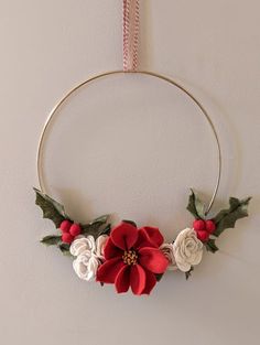 a christmas wreath hanging on the wall with red and white flowers