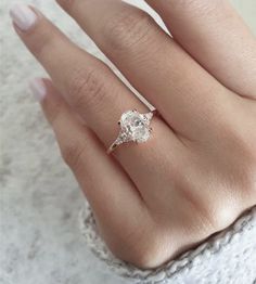 a woman's hand with a diamond ring on her finger and the other hand holding an engagement ring