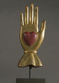 a gold statue with a heart on it's palm and two hands in the shape of a hand