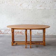 a wooden table sitting in front of a white brick wall with no one around it