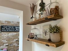 two wooden shelves with pots and plants on them next to a brick wall in a room