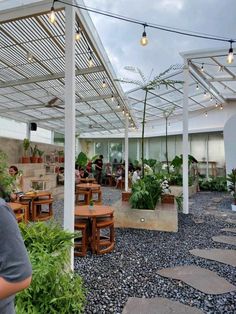 people are sitting at tables under the pergolated roof in an open area with potted plants