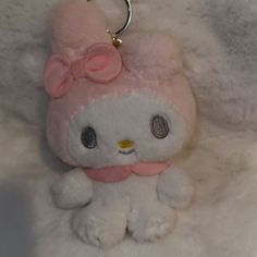 a white stuffed animal with a pink bow on it's head sitting on a furry surface