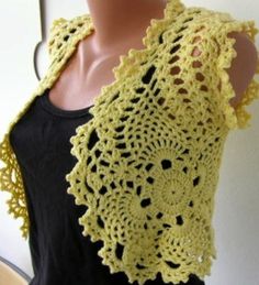 a woman wearing a yellow crocheted shawl on top of a mannequin