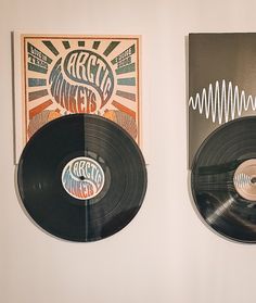 two vinyl records are hanging on the wall next to each other, one is black