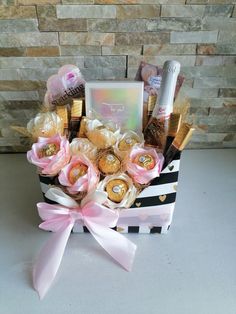 a gift basket filled with chocolates, candies and candy bar wrapped in pink ribbon