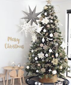 a decorated christmas tree in a living room with white and silver decorations on the top