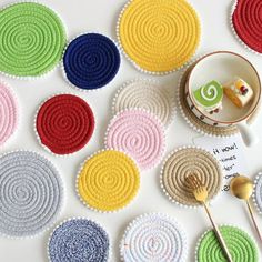 colorful crocheted coasters with spoon and plate on white table top next to each other