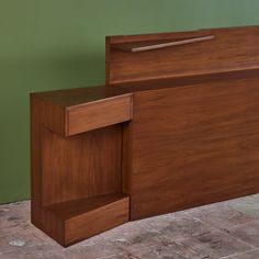 a wooden bed frame sitting on top of a tile floor next to a green wall