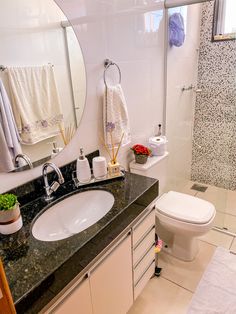 a white toilet sitting next to a bathroom sink under a large mirror on top of a counter