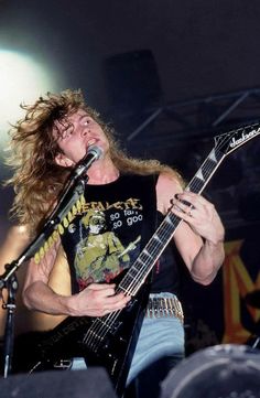 a man with long hair playing guitar on stage