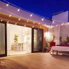 an outdoor patio with lights strung over it and a table set for two on the deck