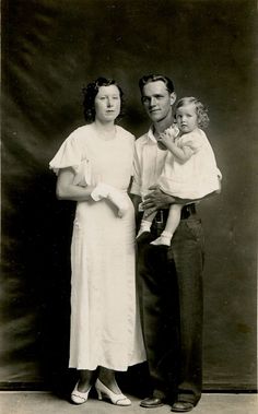 an old black and white photo of a man holding a baby with two women standing next to him