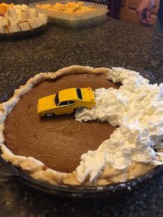 a chocolate pie with whipped cream and a yellow car on top is sitting on the counter