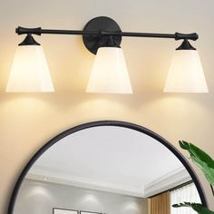 three light bathroom fixture with white glass shades and black metal frame, in a living room setting