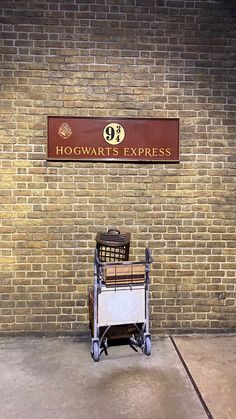 a cart sitting in front of a brick wall with a hogwart's express sign above it