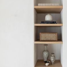 three shelves with vases and books on them