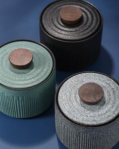 three rolls of fabric sitting next to each other on a blue surface with a wooden button in the middle