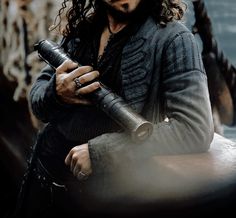 a man with long hair holding a camera in his right hand and looking off into the distance
