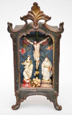 an antique clock with figurines on it's sides and a crucifix in the middle