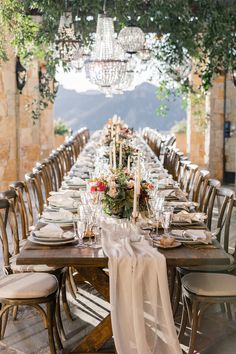 a long table is set with place settings and flowers