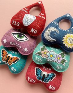 four handmade baby bibs with embroidered designs on them, one has an eye and the other has a butterfly