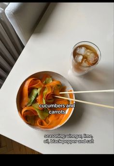 a bowl of food with chopsticks next to it on a white table top