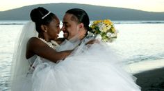 a bride and groom embracing each other on the beach