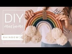 a woman holding up a rainbow made out of yarn and pom - poms