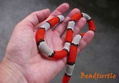a hand holding an orange and white snake in it's left hand with the word bead turtle written on it