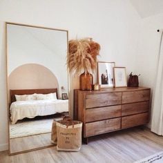 a bedroom with a dresser, mirror and pictures on the wall next to a bed