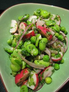 a green plate topped with peas and radishes