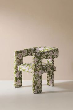 a green chair sitting on top of a white floor next to a vase with flowers