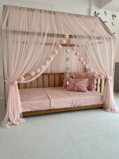 a pink canopy bed with curtains and pillows