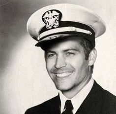 a black and white photo of a man in a sailor's uniform smiling at the camera