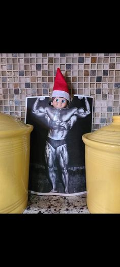 an elf is standing next to two yellow containers with a picture on the front and back