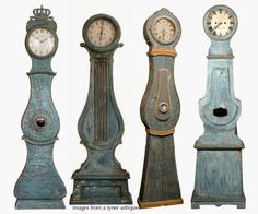 four old clocks are standing side by side in different styles and colors, one is blue the other is green