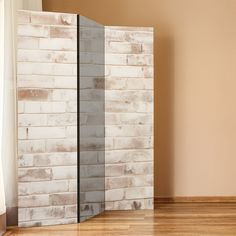 an empty room with a brick wall and wooden flooring in front of the door