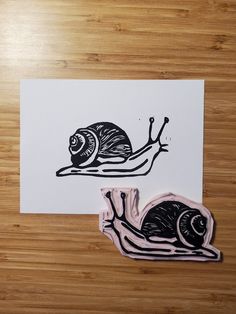 a snail is sitting on top of a piece of paper next to a sticker