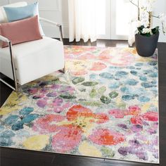 a white chair sitting on top of a wooden floor next to a rug covered in flowers