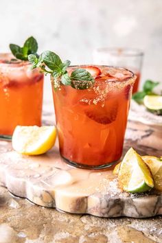 two glasses filled with watermelon lemonade and mint garnish on a marble slab