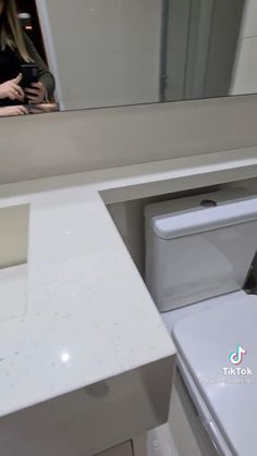 a woman is taking a selfie in the bathroom mirror while looking at her cell phone