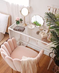 a pink chair sitting in front of a mirror on top of a desk next to a potted plant