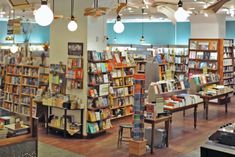 the inside of a bookstore with lots of books on shelves and lamps hanging from the ceiling