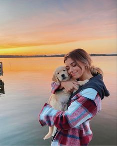 a woman holding a dog in her arms near the water